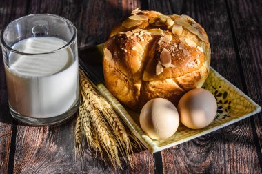 Tahta bir masada kahvaltı ekmek, yumurta ve bir bardak süt. 