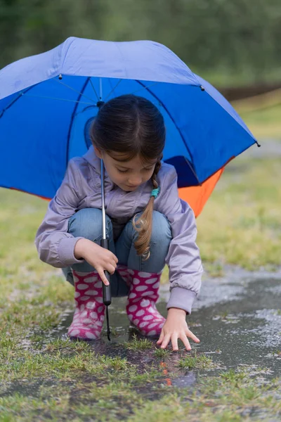 Fille avec un parapluie sous la pluie jouer — Photo