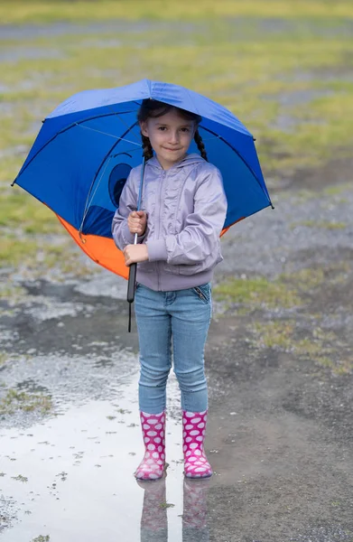 Chica con un paraguas en la lluvia jugando —  Fotos de Stock