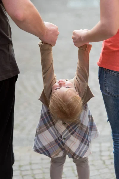 Rodzice, trzymając córkę za ręce — Zdjęcie stockowe