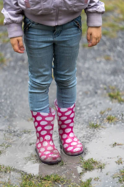 Gummistiefel plätschern durch eine Regenpfütze — Stockfoto