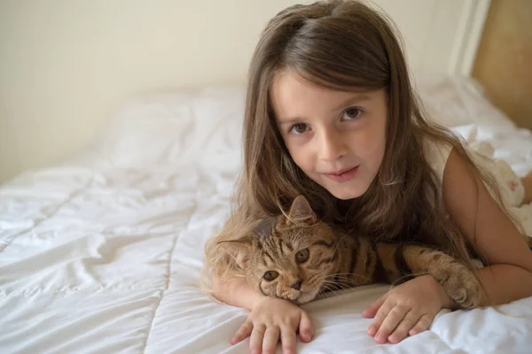 Niño jugando con gato en la cama — Foto de Stock