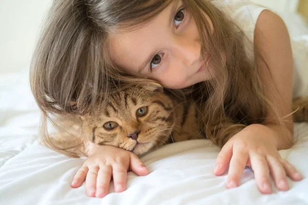 Kind spielt mit Katze auf Bett — Stockfoto