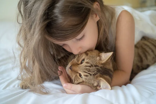 Niño jugando con gato en la cama — Foto de Stock