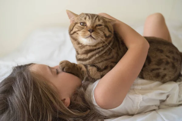 Caucasian girl hugging cat on bed — Stock Photo, Image