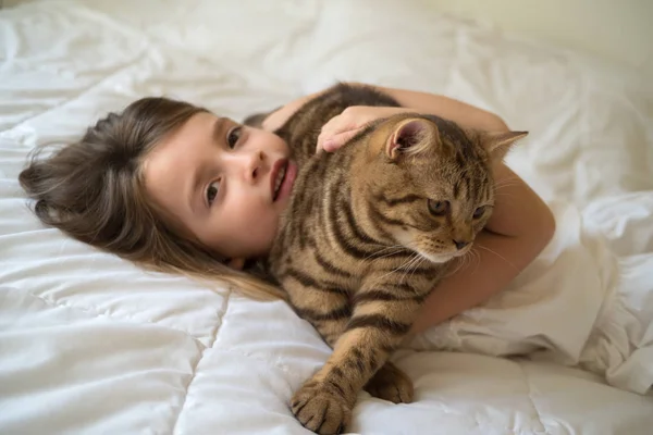 Белая девушка обнимает кошку на кровати — стоковое фото