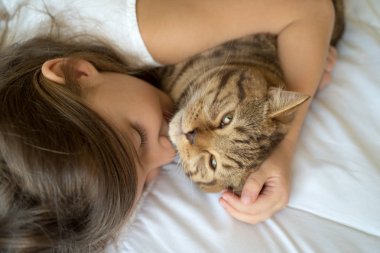 Genç kızla yatakta yatarken kedi