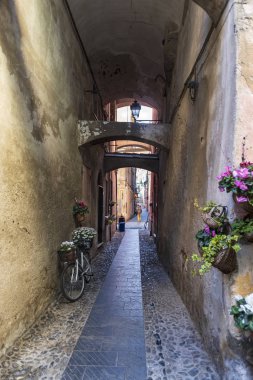 Finale Ligure, İtalya - 8 Nisan 2019: İtalya 'nın Liguria bölgesindeki Savona ili Finalborgo ilindeki ortaçağ köyünde dar bir sokak boyunca görüntüle