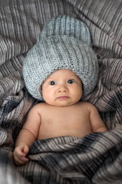Portrait of a newborn baby wearing hat and wrapped in brown blanket clipart