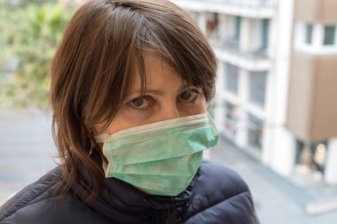 Ağzına koruyucu maske takmış yetişkin bir kadının portresi.