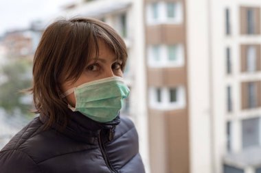 Ağzına koruyucu maske takmış yetişkin bir kadının portresi.