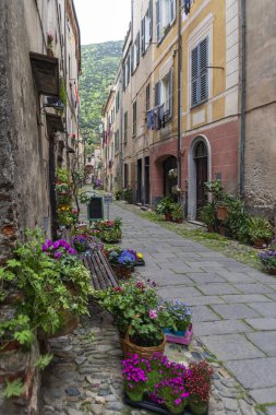 İtalya 'nın Liguria bölgesindeki Savona eyaletinin Finalborgo ilindeki ortaçağ köyünde dar bir sokak boyunca manzarayı izle
