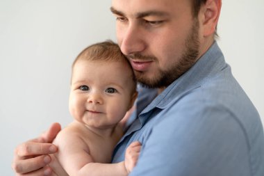 Genç baba yeni doğmuş kızını kucağında tutuyor.