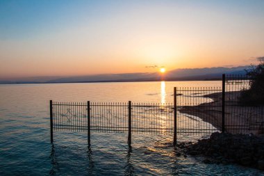 Güzel göl, gün batımındaki dağların silueti mavi gökyüzü ve suyun yansıması.