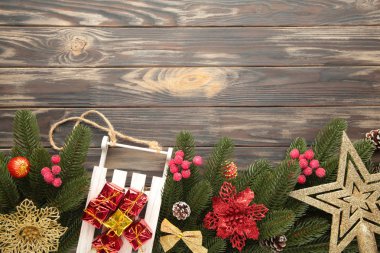 Kahverengi ahşap arka planda köknar ağacı dalı olan Noel oyuncak kızağı..