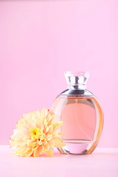 Flacon de parfum avec fleur sur fond rose — Photo
