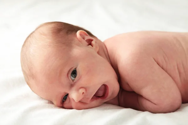 Baby Mädchen auf Bauch auf weißem Bett liegend, Ansicht von oben — Stockfoto