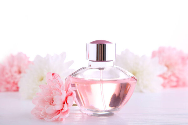 Perfume bottle with flowers on white background, top view