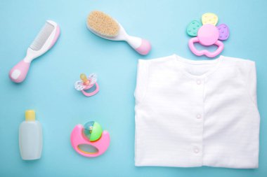 Mavi arka planda duş aksesuarları olan bebek kıyafetleri.