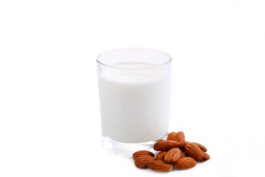 Badem sütü bardakta ve bademler beyaz arkaplanda izole.