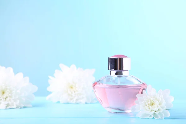 Bottle of perfume with flowers on blue background — Stock Photo, Image