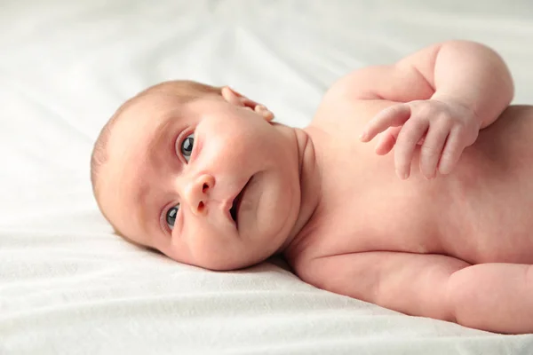 Baby girl lying on white bed, top view — Stock Photo, Image