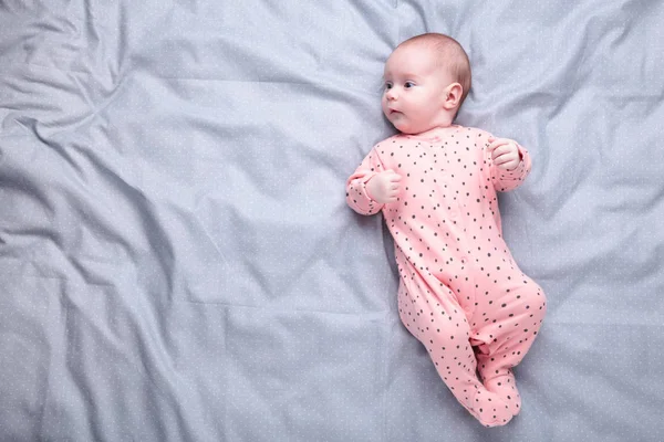 Niedliches Baby auf dem grauen Bett mit Kopierraum — Stockfoto
