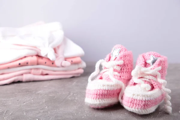 Babystiefel mit Kleidung auf grauem Hintergrund — Stockfoto