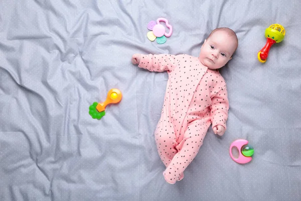 Cute baby playing with colorful rattle toy. New born child, little girl looking at the camera and crawling. — Stock Photo, Image