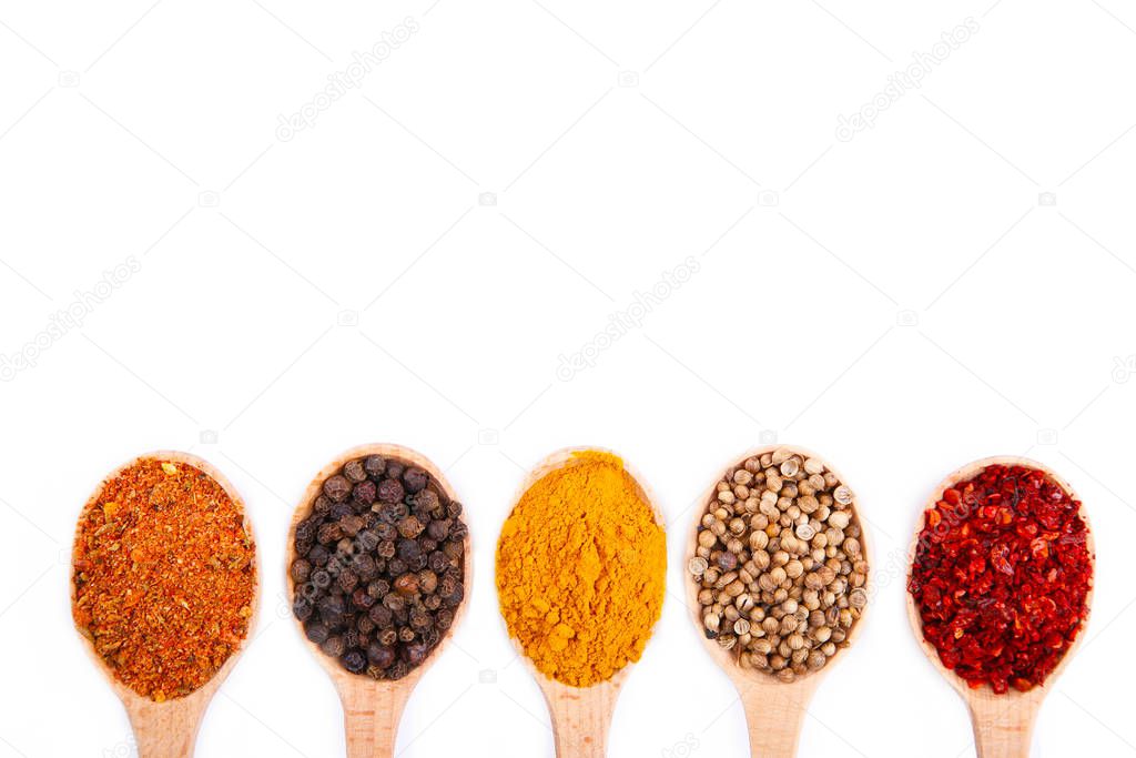 Spices mix on wooden spoons on a white wooden background. Top view
