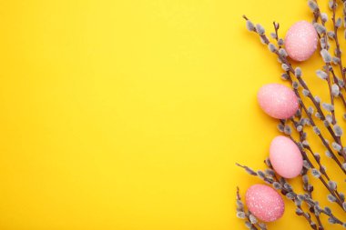 Sarı arka planda pembe paskalya yumurtaları ve söğüt dalları