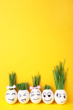 Fotokopi alanı olan yeşil çimenli güzel el yapımı yumurtalar. Sarı arka planda Paskalya konsepti