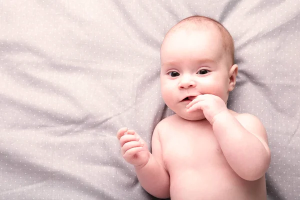Söt baby liggande med fingrarna i munnen, ovanifrån — Stockfoto