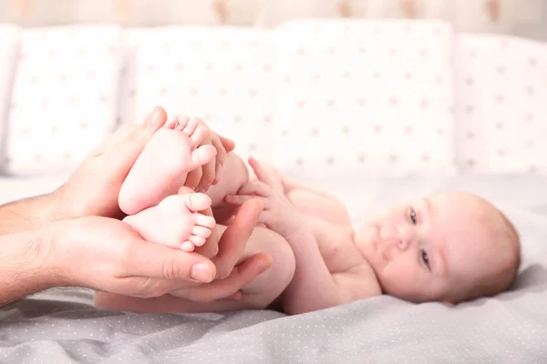 Vater hält kleine Babyfüße auf dem Bett — Stockfoto