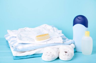 Mavi arka planda duş aldıktan sonra taraklı ve beyaz terlikli çocuk kıyafetleri.