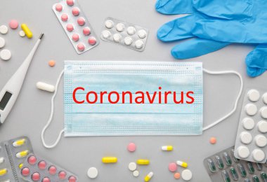 Tıbbi termometre ve maskeli gri haplar. Coronavirus yazıtları