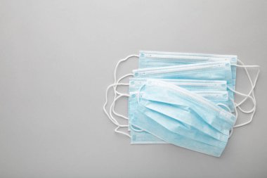 Gri arka planda tıbbi maskeler. Coronavirus, üst görünüm