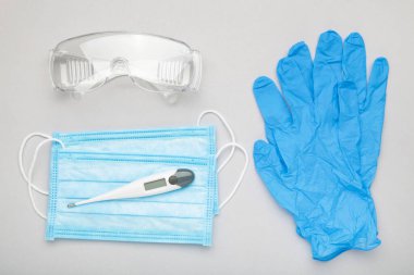 Gri arkaplandaki virüslere karşı korunmak için gözlük ve tıbbi tek kullanımlık maske. Covid 19