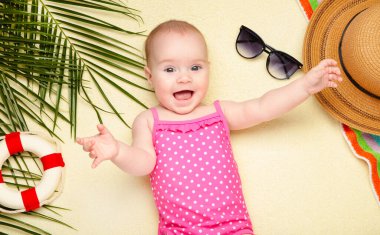 Plaj aksesuarlarıyla gülümseyen bebek. Bebekle deniz tatili, yaz konsepti. Üst görünüm