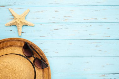 Deniz kabuklu plaj şapkası ve mavi arka planda güneş gözlüğü, düz yatıyordu.