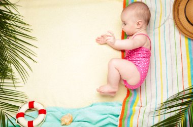 Plaj aksesuarları olan tatlı bir kız. Bebekle deniz tatili, yaz konsepti. Üst görünüm