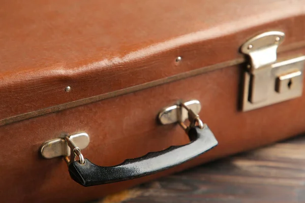 Old shabby leather portable suitcase for travel trip on brown background. Top view