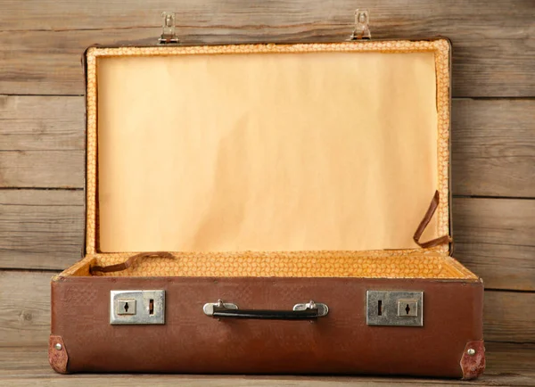 Open old shabby leather portable suitcase for travel trip on grey wooden background. Top view