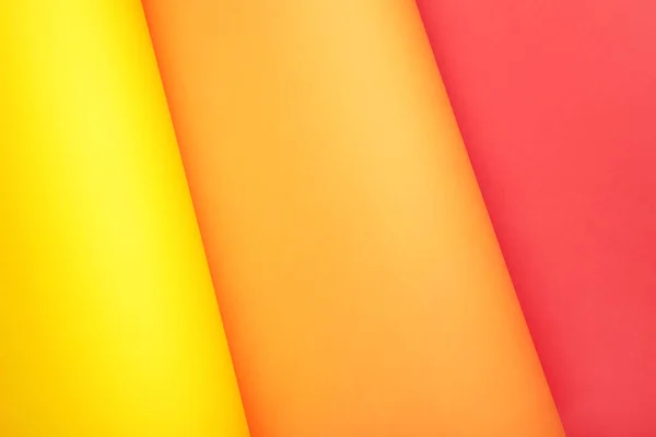 Color papers flat composition background with yellow, orange and red color with copy space. Top view