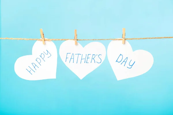 Happy Fathers Day written on paper hearts on blue background. Top view