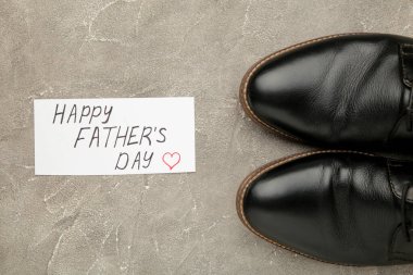 Babalar Günün kutlu olsun mesajı ve çimento kaplı siyah ayakkabılar. Üst görünüm