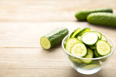 Gri ahşap arka planda kasede taze salatalık dilimleri. Üst görünüm