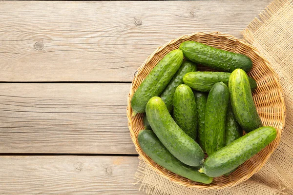 Gri ahşap arka planda sepetteki taze salatalıklar. Üst görünüm