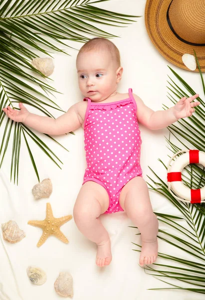 Plaj aksesuarları olan tatlı bir kız. Bebekle deniz tatili, yaz konsepti. Üst görünüm