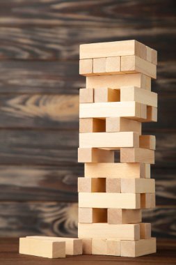 Ahşap Jenga oyununda iş riski kavramı. Kahverengi arkaplanda tahta bloklar